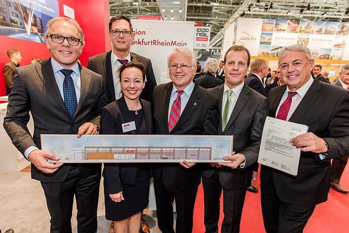 Die GHI-Gesellschafter Jörg Fischer und Stefan Kraus, dazwischen Eva Reich von der REWE-Expansionsabteilung und Bürgermeister Hans-Georg Brum, rechts Arnold Richter von der Stadtentwicklung Oberursel bei der Übergabe der Baugenehmigung für einen neuen REWE-Markt in Oberursel-Oberstedten. Hinten links im Bild Stefan Haja, ebenfalls REWE.