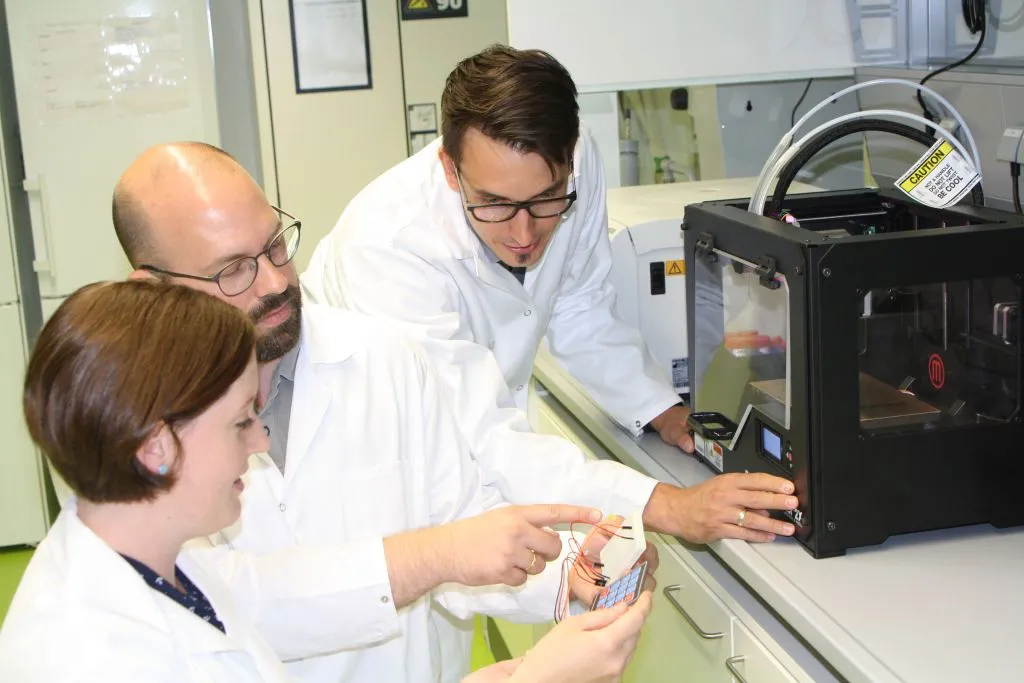 Dipl.-Ing. Anna Eicher, Dr. Thomas Schmidts und Dipl.-Ing. Sören Wildenhain (von links) vom Projektteam der THM nutzen im Labor einen 3D-Drucker, um Komponenten des LED-Systems herzustellen. Foto: TH Mittelhessen